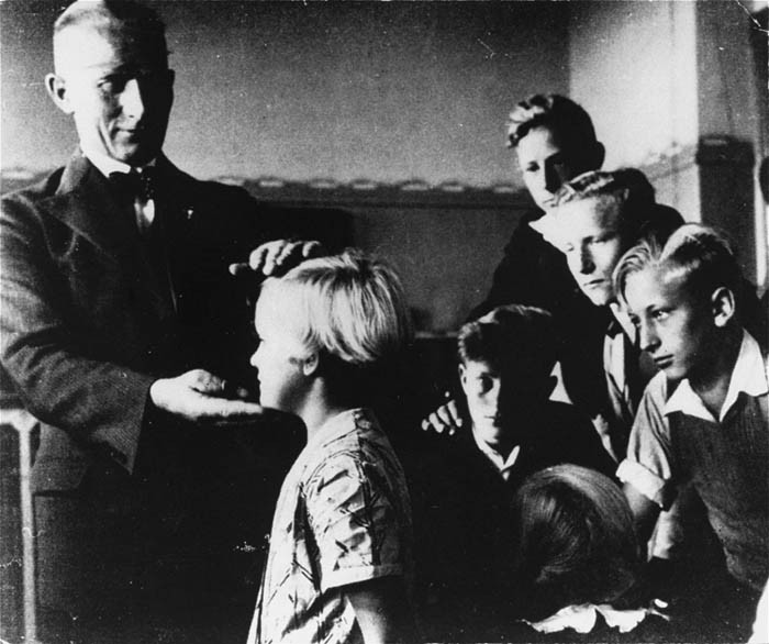 A German teacher singles out a child with "Aryan" features for special praise in class.